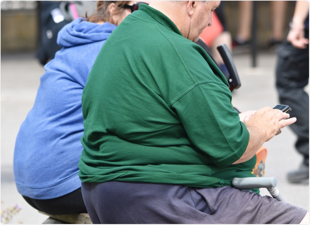 Obese adults sat on bench in town centre