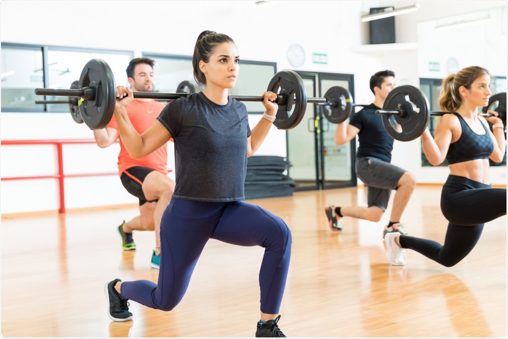 Woman doing weightlifting as part of exercise class at local gym.