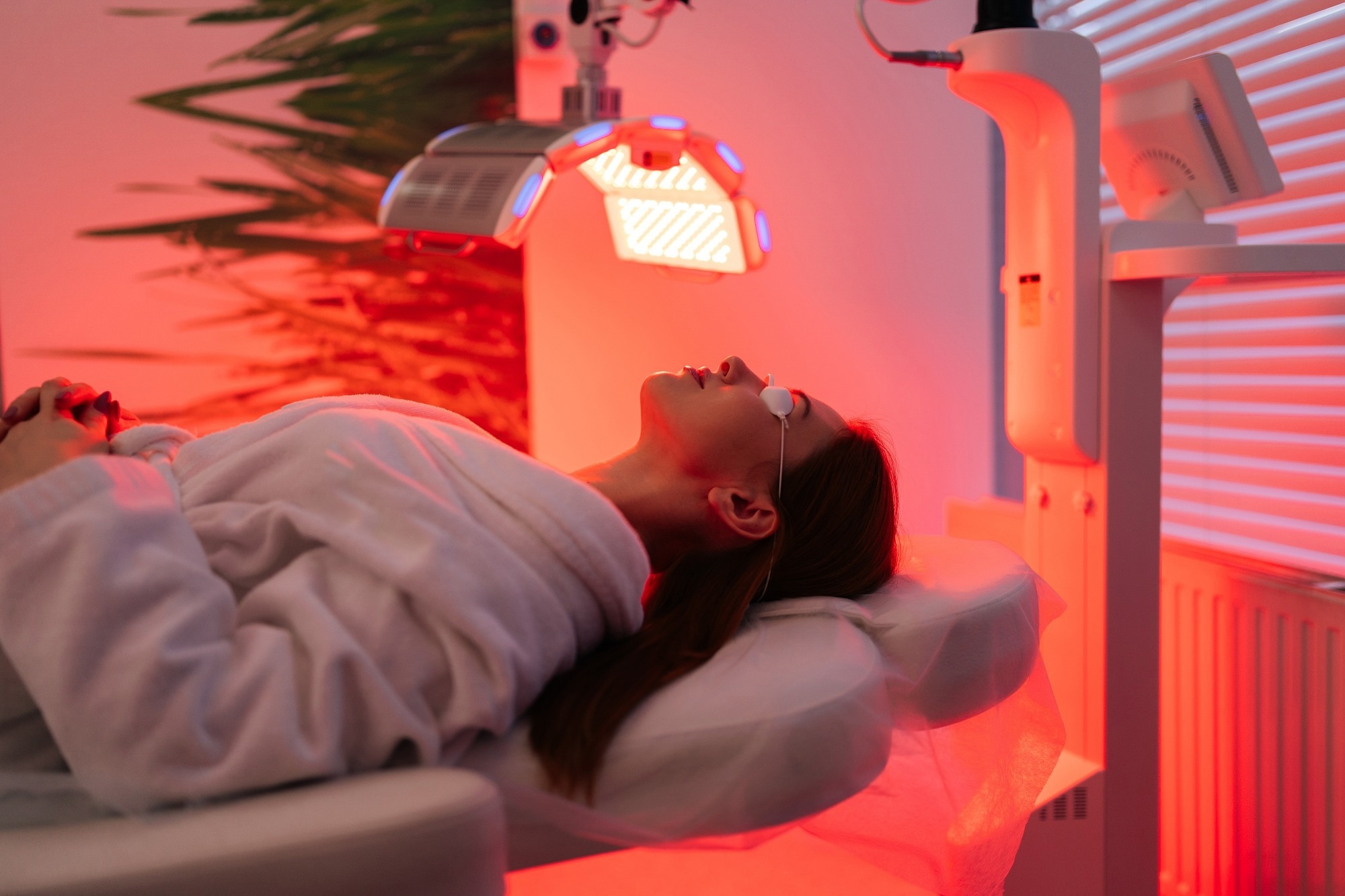 Side view of female patient undergoes red LED light or RLT therapy for skin rejuvenation at modern luxury aesthetic clinic.