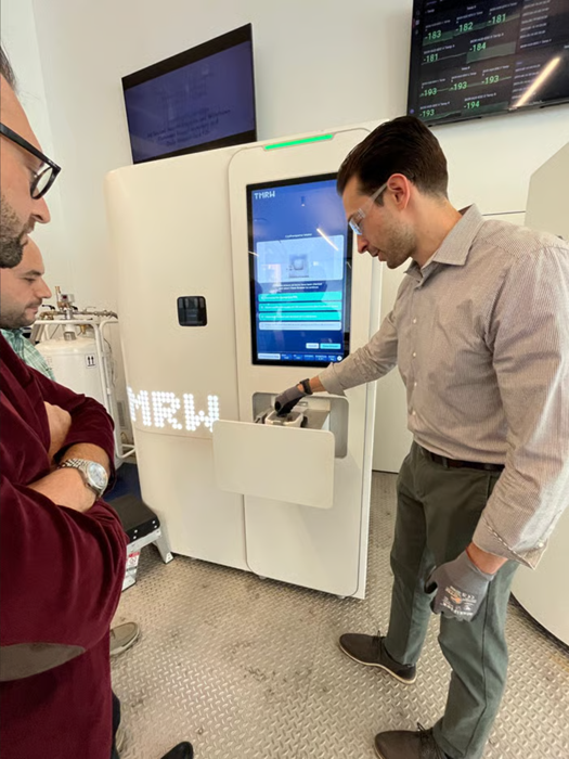 A man demonstrating use of the new technology, as two other men watch his dmeonstration.
