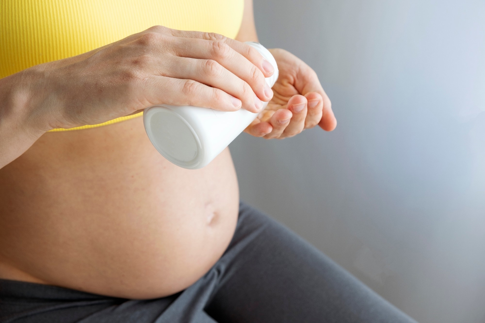 Woman with pregnant belly hold medicine jar in hands