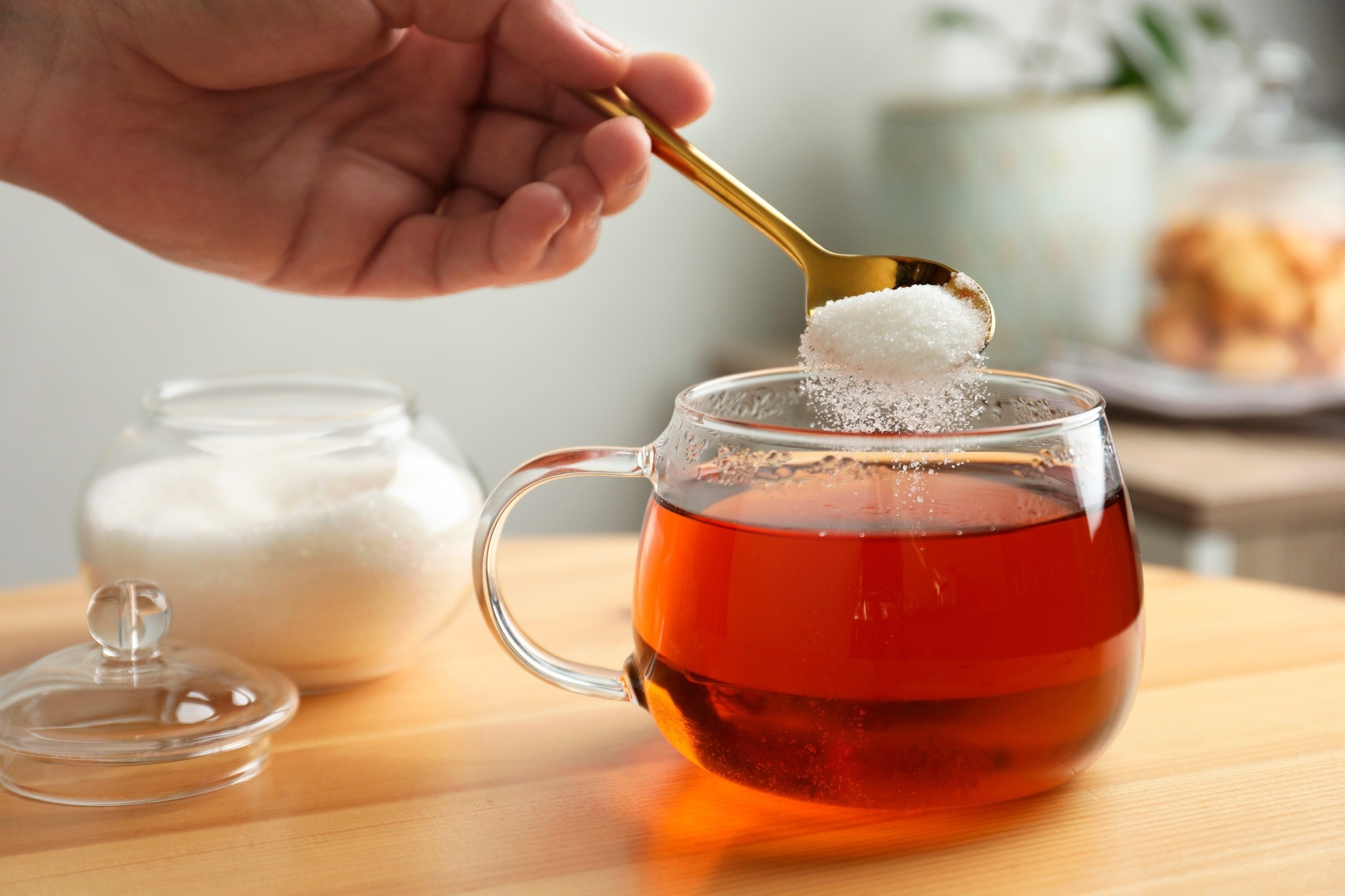 Woman adding sugar into aromatic tea