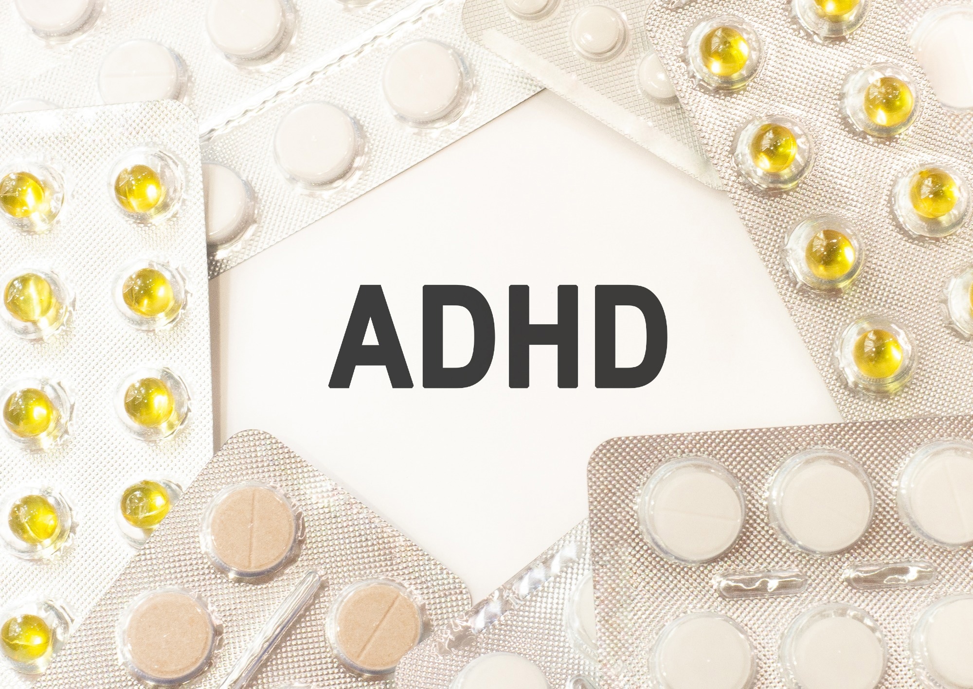 Text adhd on white background. There are various pills and vitamins around