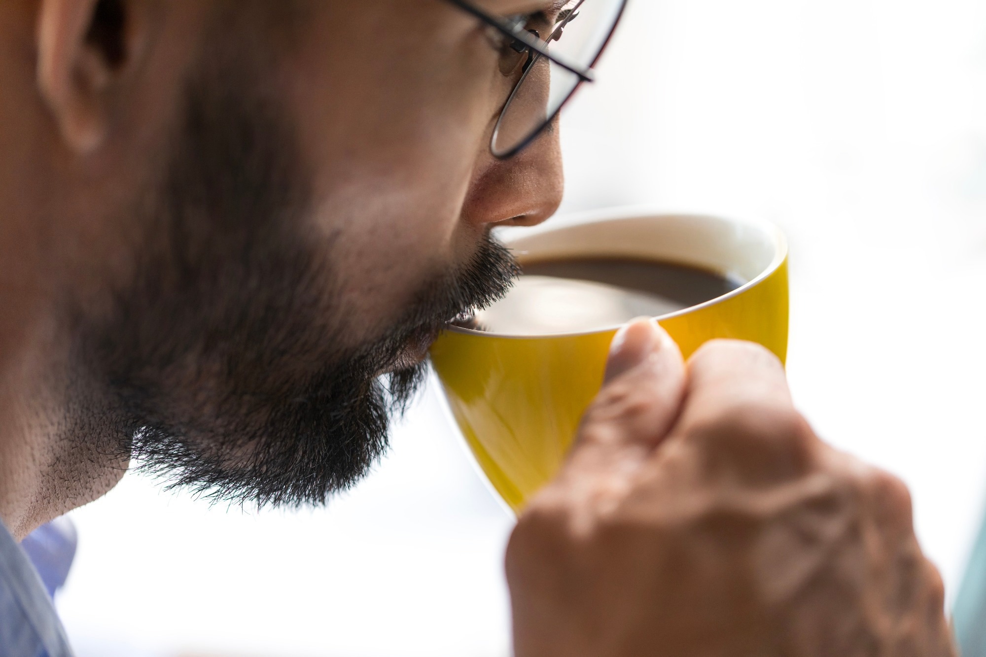 Close-up of a bearded business man drinking coffee in the office, white background