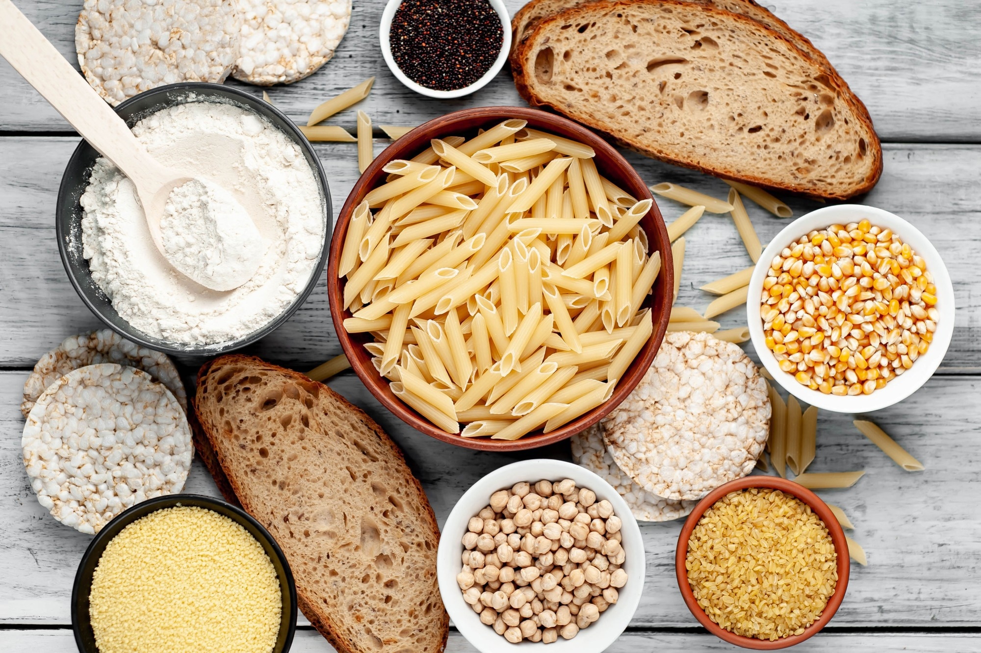 Selection of gluten free food. Chickpeas, bread, couscous, bulgur, pasta, bread, flour, quinoa on wood background