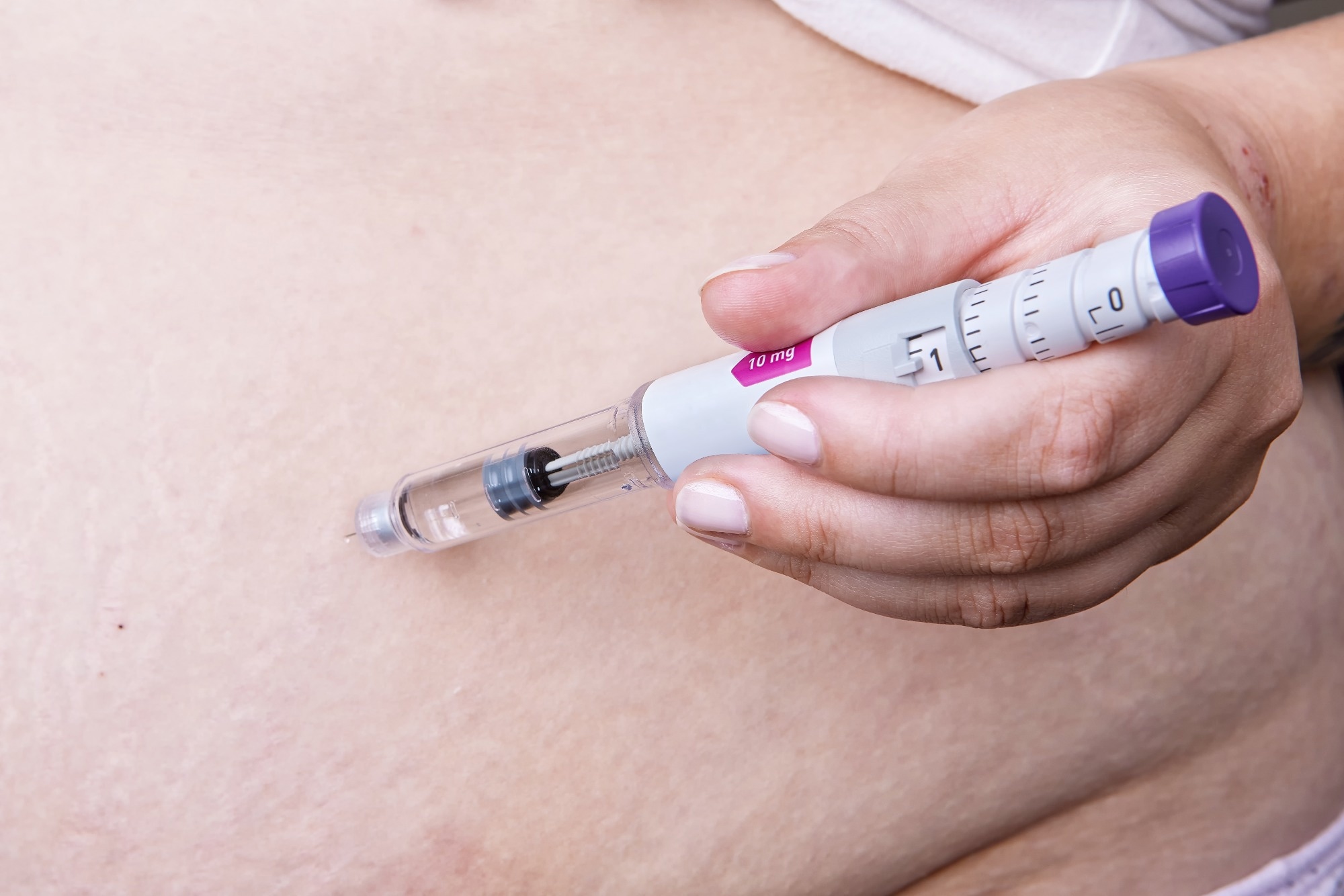 Person using Mounjaro insulin injector pen or GLP-1 injection for shot in abdomen.