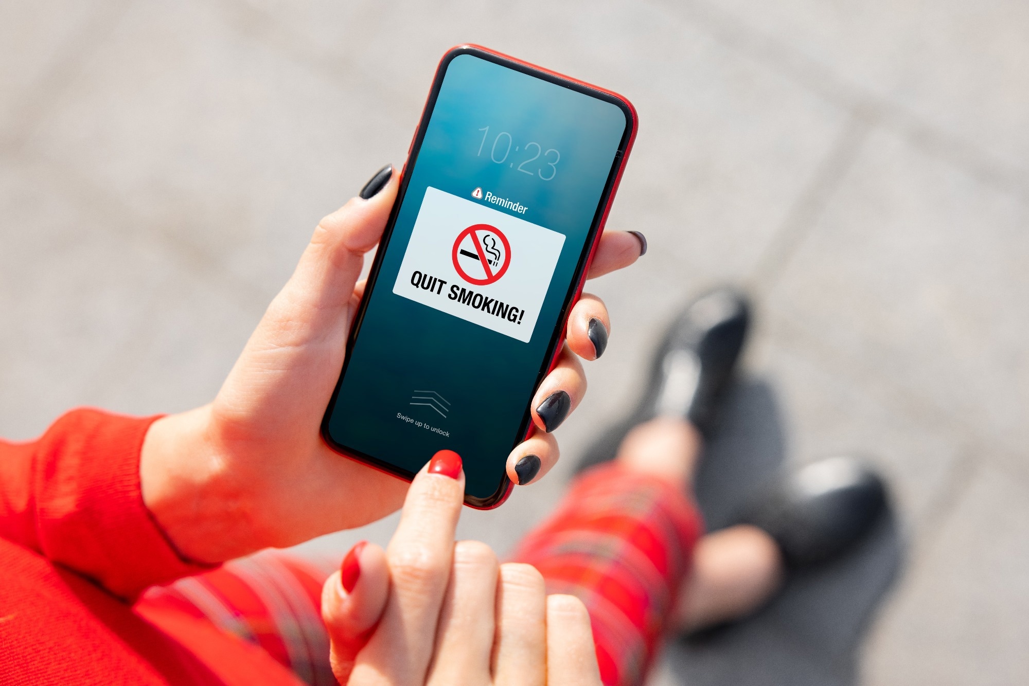 Woman holding mobile phone and looking at pop-up notification reminding to quit smoking