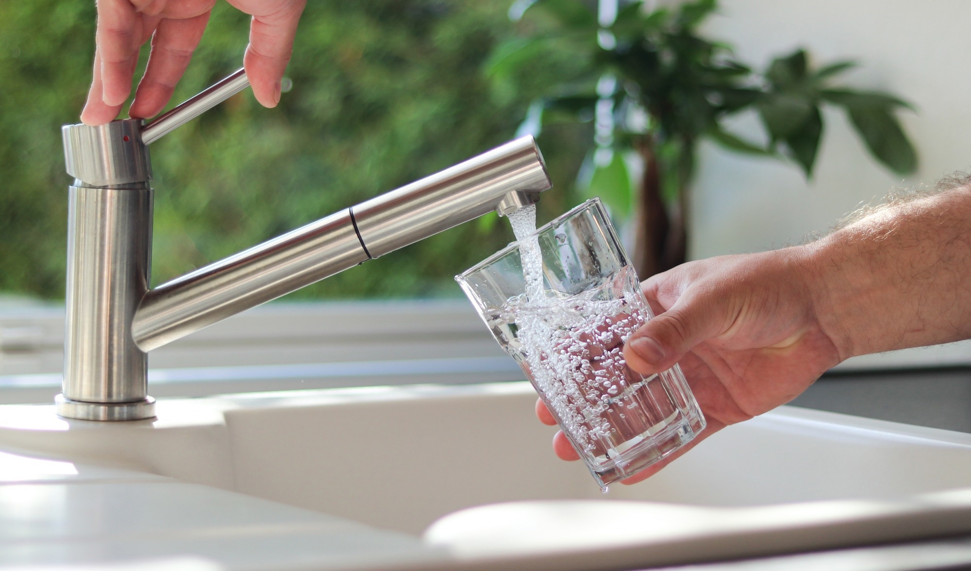 Close up of male hands pouring tap water into a glass in the kitchen